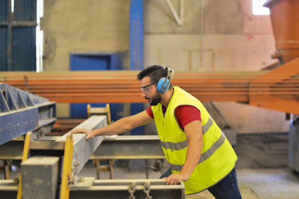 Man wearing eye and ear protective gear working in a factory