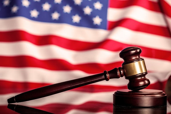 A judge's gavel with the American flag in the background.